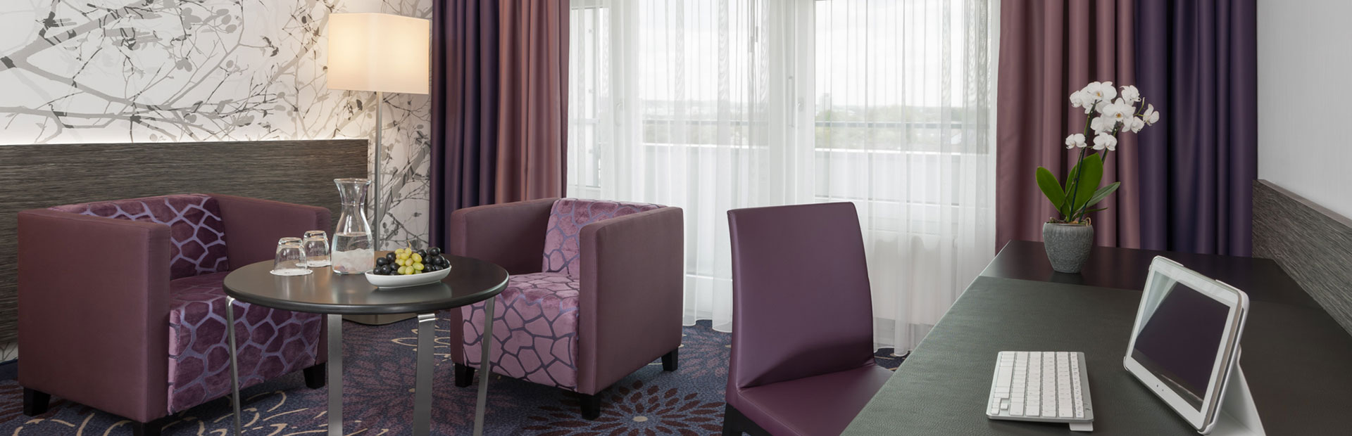 Standard-Zimmer mit lila Sitzecke im SI-SUITES Hotel Stuttgart